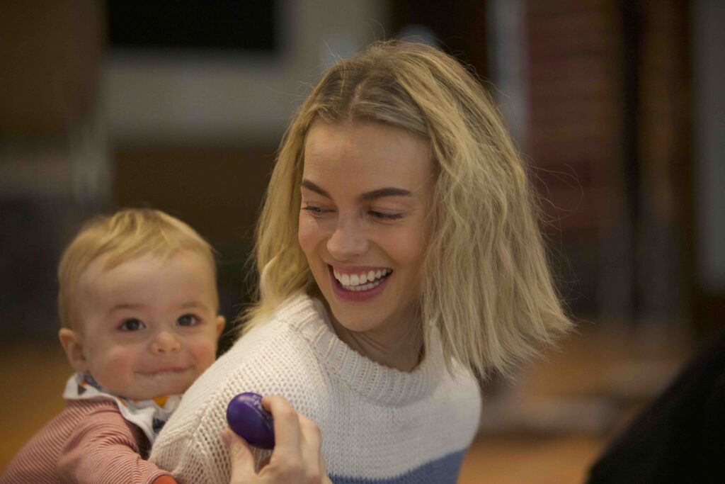 Mom and baby laughing while playing with a shaker in music class